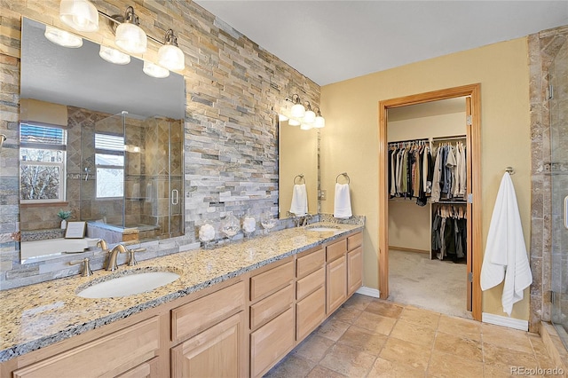 bathroom with a tile shower, double vanity, baseboards, and a sink