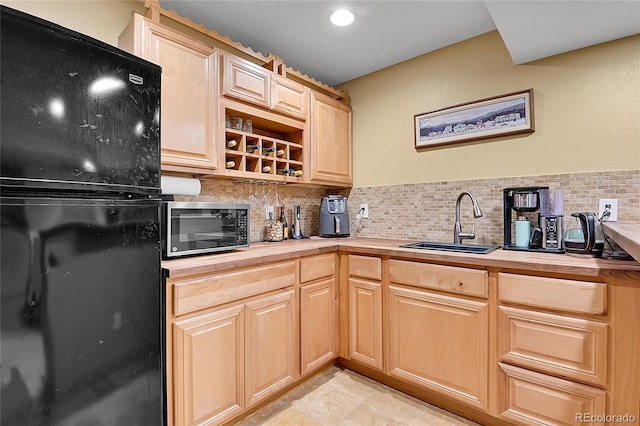 kitchen featuring light brown cabinetry, a sink, tasteful backsplash, freestanding refrigerator, and wooden counters