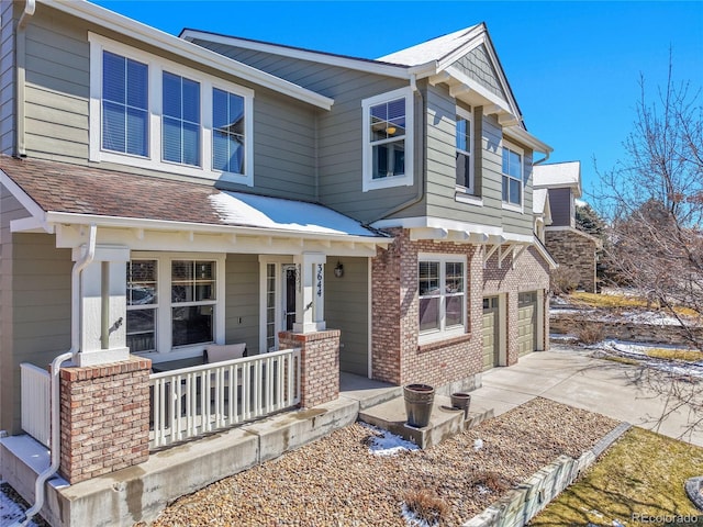 view of front of property with brick siding, a shingled roof, concrete driveway, covered porch, and an attached garage