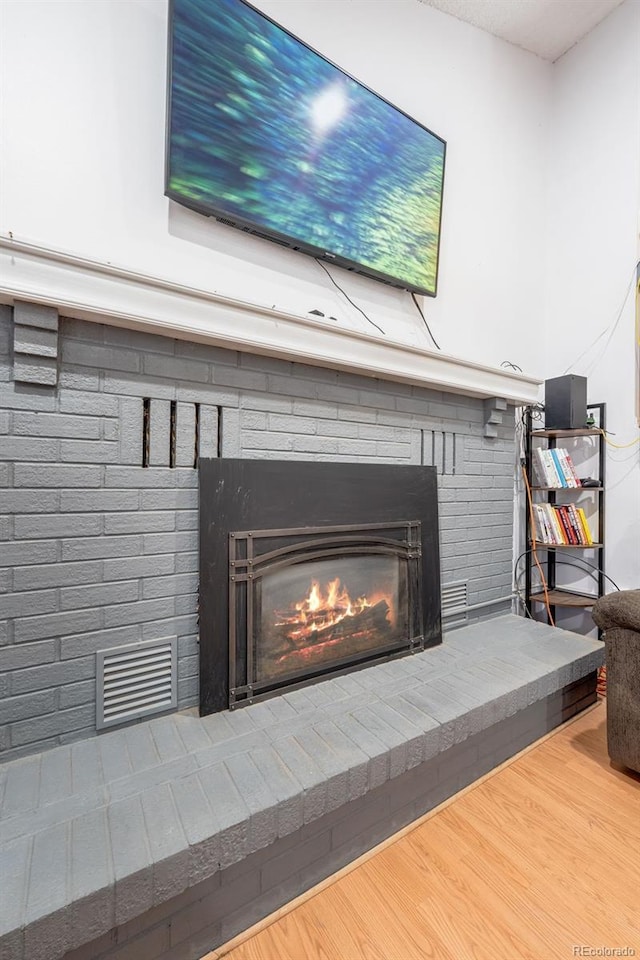 interior details featuring a fireplace, wood finished floors, and visible vents