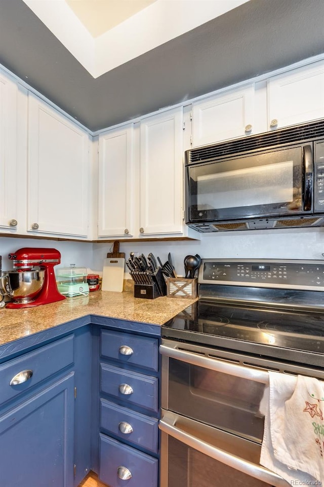 kitchen with black microwave, light countertops, white cabinetry, and double oven range