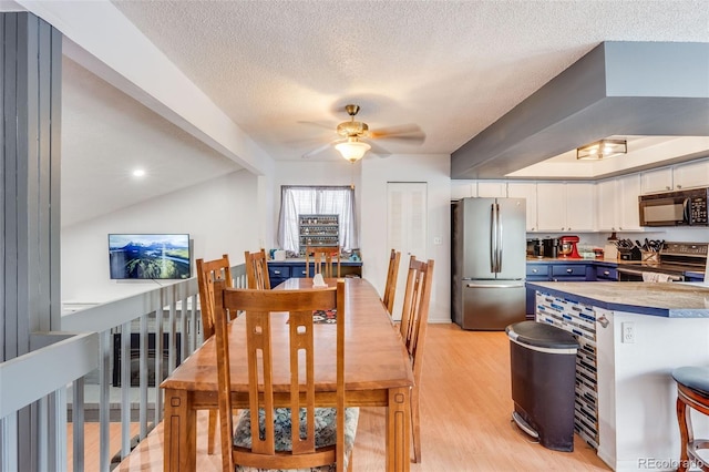 dining room featuring a textured ceiling, light wood-type flooring, and a ceiling fan