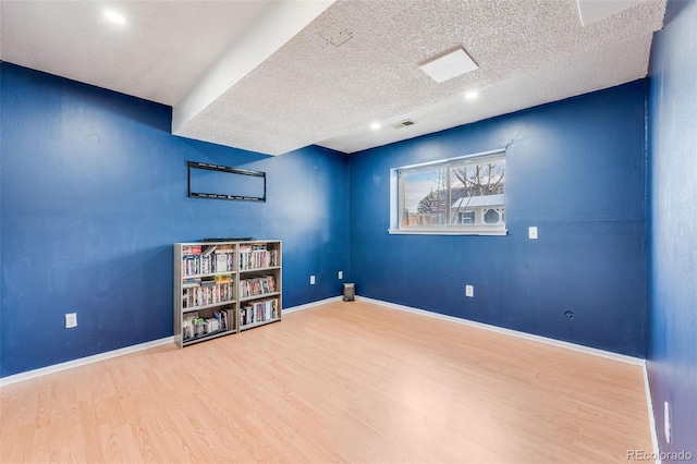 interior space with visible vents, a textured ceiling, baseboards, and wood finished floors