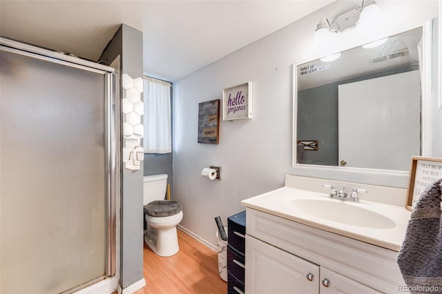 full bath with a stall shower, visible vents, toilet, wood finished floors, and vanity