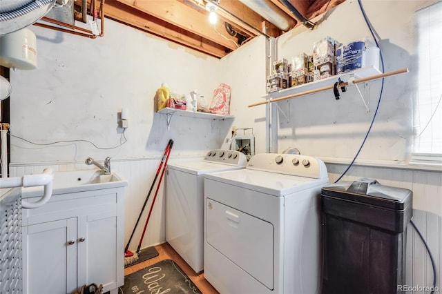 laundry room with wood finished floors, washer and clothes dryer, wainscoting, and a sink