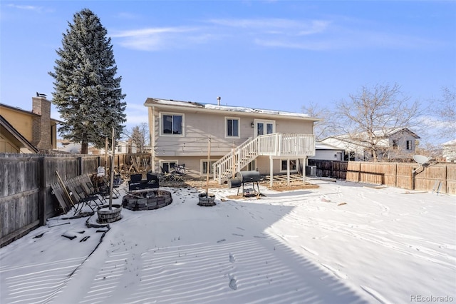 snow covered house with an outdoor fire pit, central AC unit, a fenced backyard, stairway, and a wooden deck