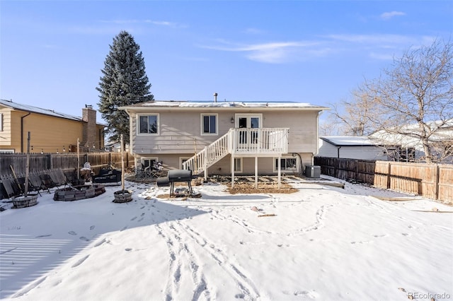 snow covered back of property featuring stairway, cooling unit, a fenced backyard, and a fire pit