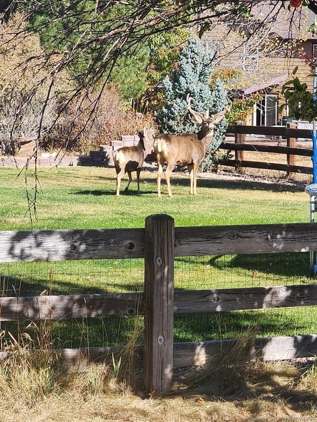 view of gate with a rural view and a lawn