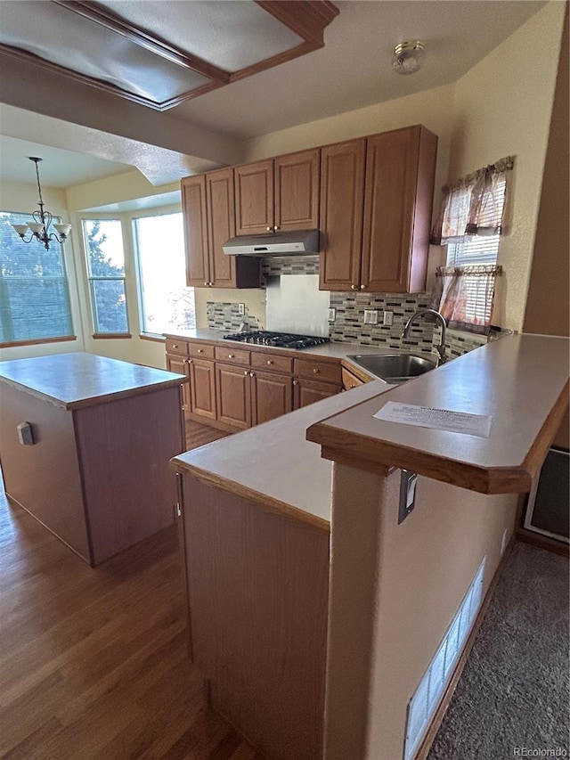 kitchen featuring a center island, sink, decorative light fixtures, kitchen peninsula, and a chandelier