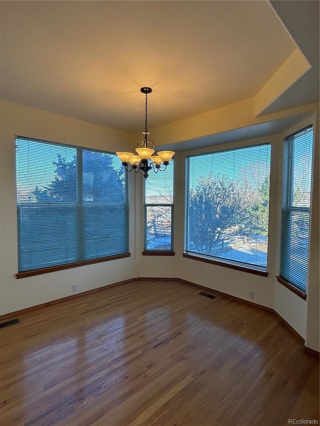 unfurnished dining area featuring wood-type flooring and an inviting chandelier