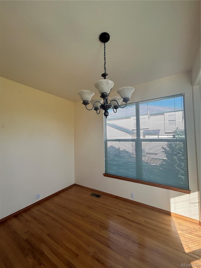 unfurnished dining area with hardwood / wood-style flooring and an inviting chandelier