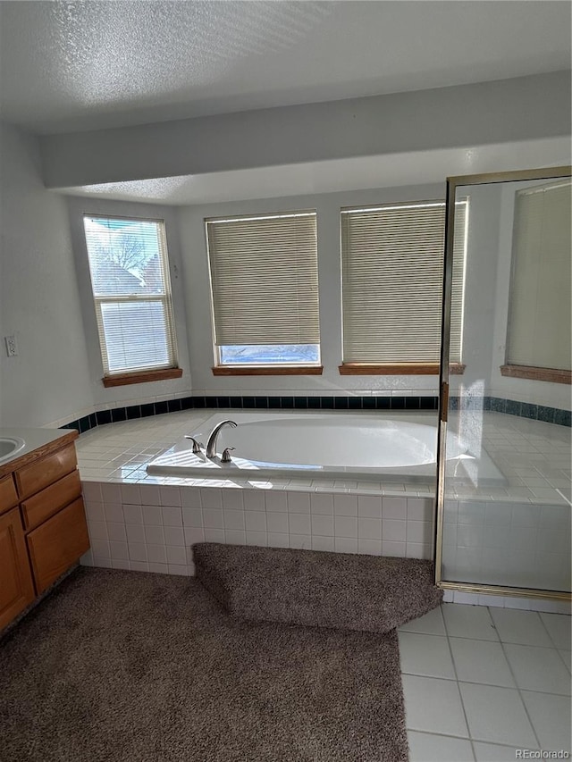 bathroom with tile patterned flooring, vanity, separate shower and tub, and a textured ceiling