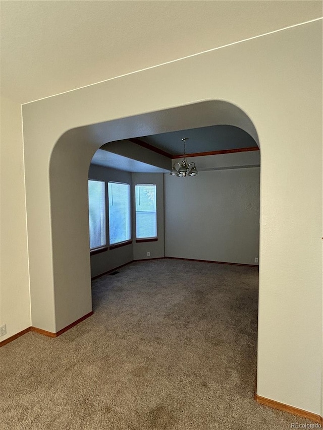 empty room with carpet and a notable chandelier