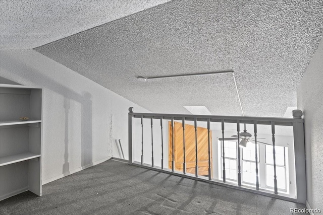 bonus room with a textured ceiling, a textured wall, a skylight, and a ceiling fan