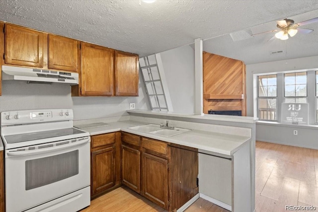 kitchen featuring white electric stove, brown cabinetry, light countertops, under cabinet range hood, and a sink