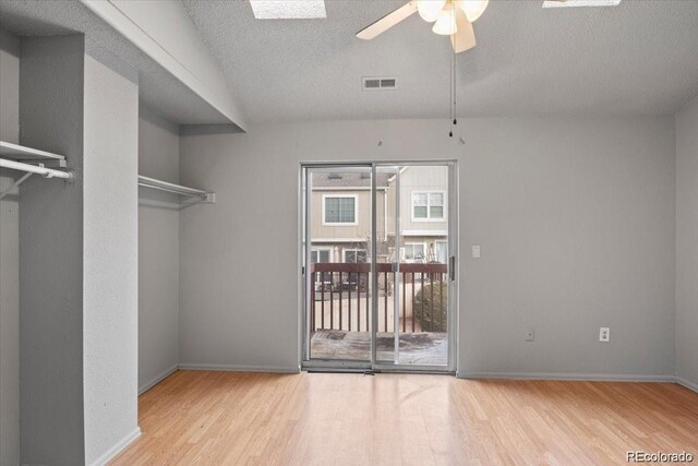 spare room with a textured ceiling, wood finished floors, visible vents, and baseboards