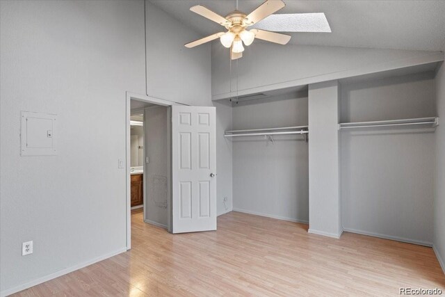 unfurnished bedroom with ceiling fan, light wood-type flooring, electric panel, vaulted ceiling with skylight, and baseboards