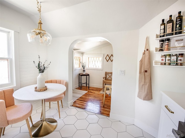 dining area with vaulted ceiling, arched walkways, and baseboards