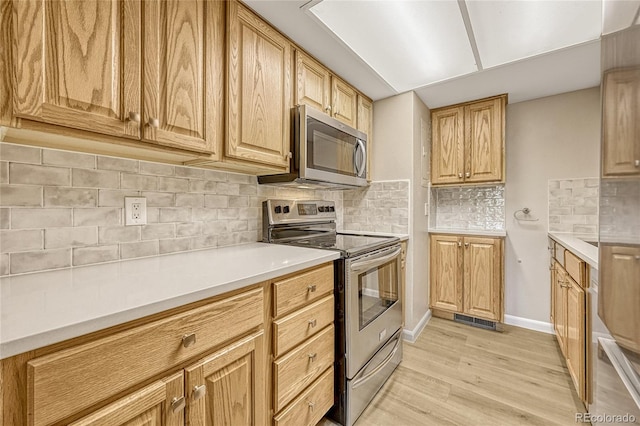 kitchen featuring light brown cabinets, decorative backsplash, light wood-type flooring, and appliances with stainless steel finishes