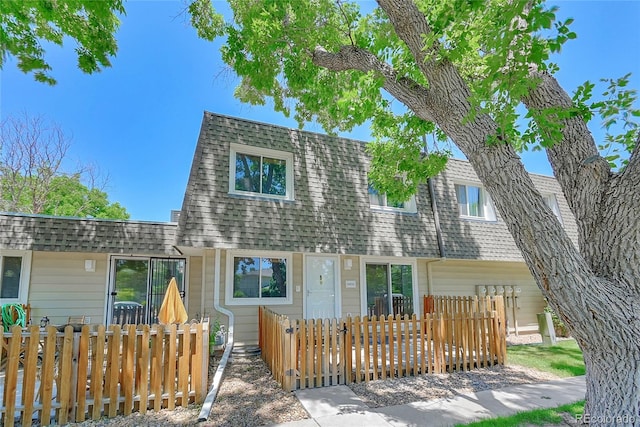 6885 E Arizona Ave Unit D, Denver, CO 80224 - view of front of house with a fenced front yard, a shingled roof, and mansard roof