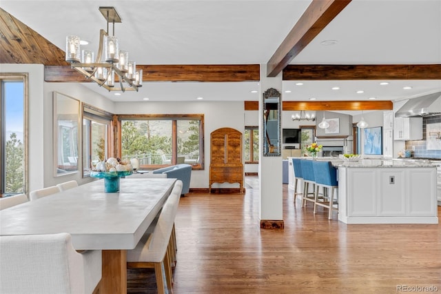 dining space with wood finished floors, a chandelier, recessed lighting, and beamed ceiling