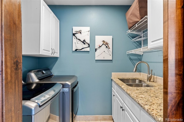 washroom featuring a sink, cabinet space, baseboards, and washer and dryer