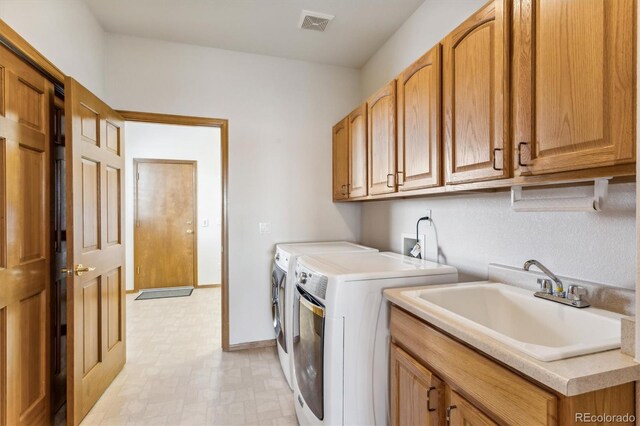 laundry room featuring cabinets, sink, and washing machine and clothes dryer