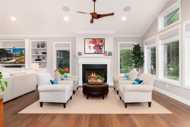 living room with hardwood / wood-style flooring, plenty of natural light, ornamental molding, and vaulted ceiling