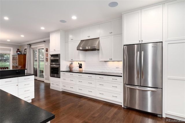 kitchen featuring wall chimney range hood, dark hardwood / wood-style flooring, white cabinets, stainless steel appliances, and backsplash