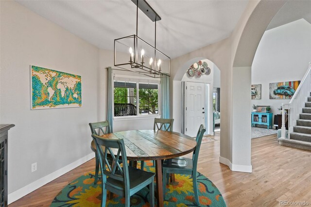 879 Quintana Ln, Erie, CO 80516 - dining area with stairs, baseboards, light wood-style flooring, arched walkways, and a chandelier