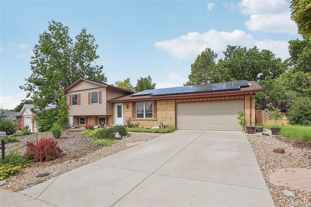 2173 S Ouray St, Aurora, CO 80013 - tri-level home with an attached garage, driveway, brick siding, and solar panels