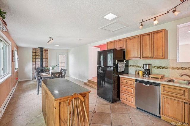 2173 S Ouray St, Aurora, CO 80013 - kitchen featuring stainless steel dishwasher, freestanding refrigerator, a baseboard heating unit, backsplash, and a textured ceiling
