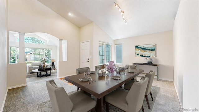 dining area featuring ornate columns, lofted ceiling, baseboards, and light carpet