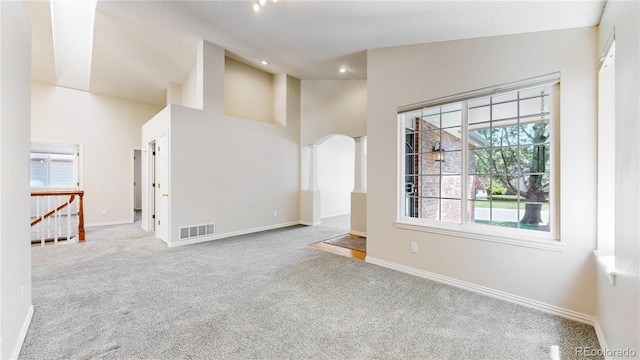 unfurnished living room featuring carpet flooring, baseboards, high vaulted ceiling, arched walkways, and recessed lighting