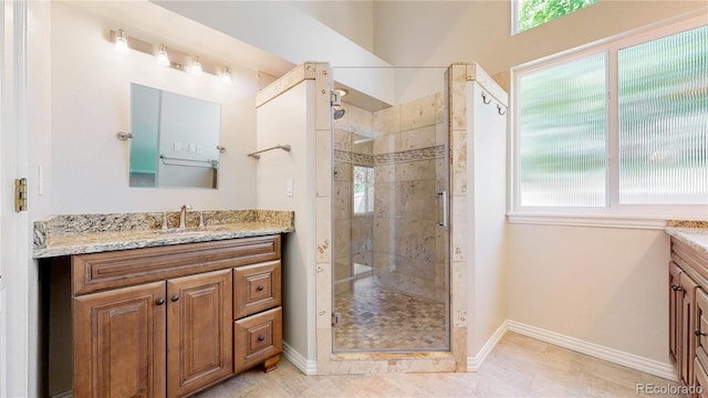 full bathroom with vanity, a shower stall, and baseboards