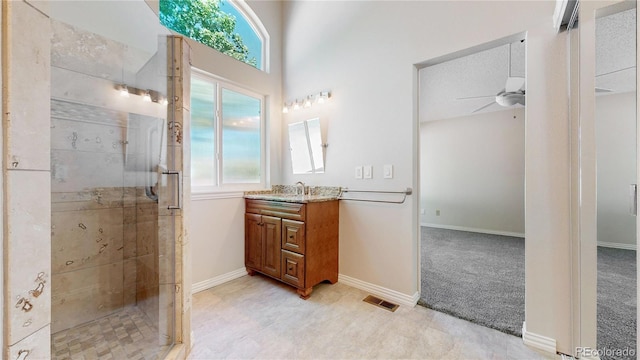 full bath with a stall shower, a ceiling fan, healthy amount of natural light, and vanity