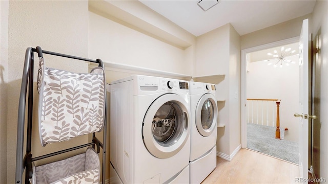 laundry room with separate washer and dryer, light wood-style floors, baseboards, and a chandelier
