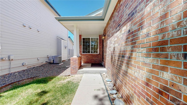 property entrance featuring brick siding and central AC unit