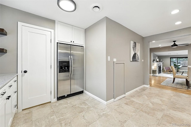 4465 Zephyr St, Wheat Ridge, CO 80033 - kitchen featuring stainless steel fridge, ceiling fan, white cabinets, light stone finish floors, and recessed lighting