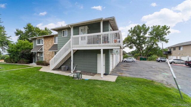 rear view of property with a lawn, a garage, and central air condition unit