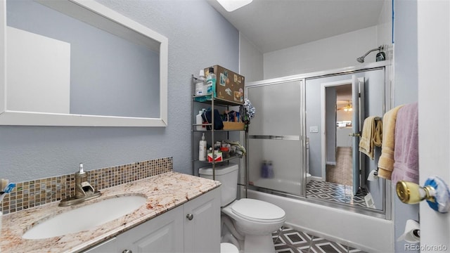 full bathroom with decorative backsplash, toilet, shower / bath combination with glass door, tile patterned flooring, and vanity