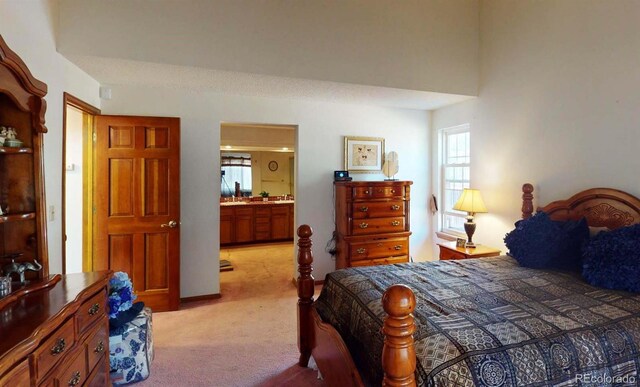 bedroom with ensuite bathroom and light colored carpet