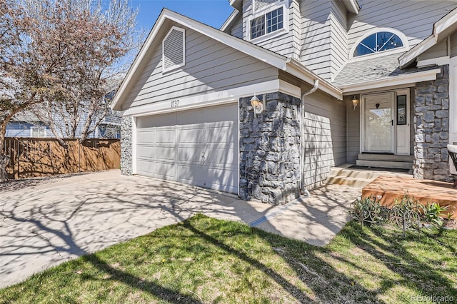garage featuring fence and concrete driveway