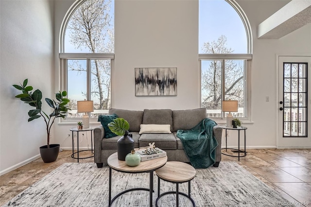 living area with baseboards and a towering ceiling