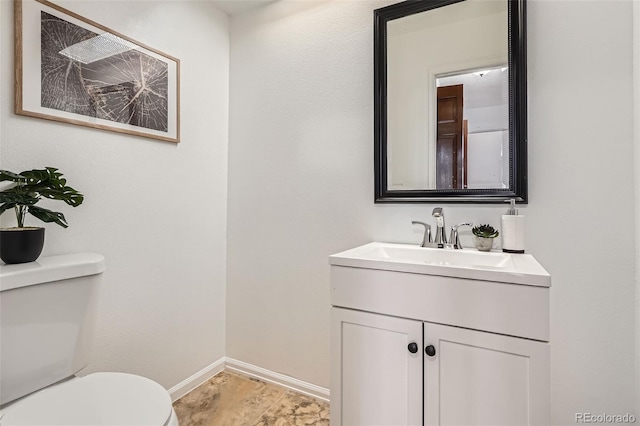 half bathroom with toilet, baseboards, and vanity