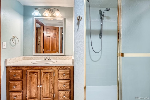 full bath featuring vanity, a textured wall, and a shower