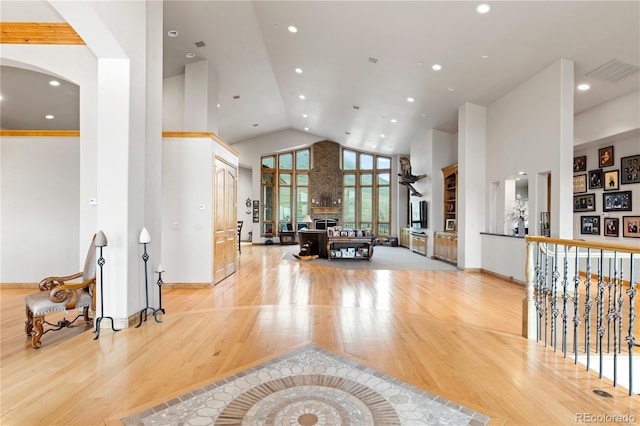 interior space featuring a fireplace, high vaulted ceiling, and light hardwood / wood-style floors