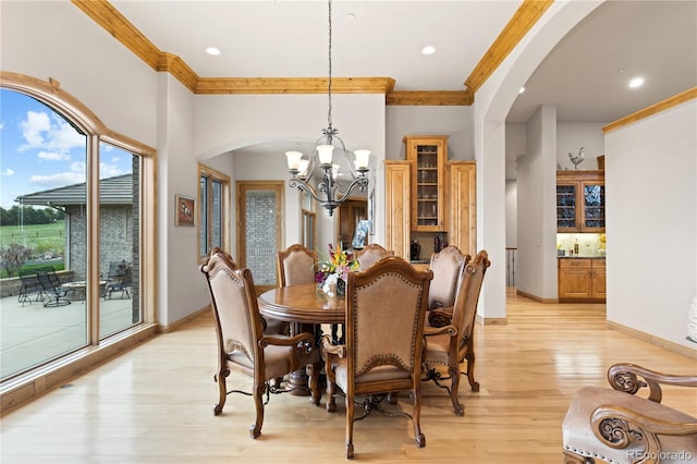 dining space with a notable chandelier, crown molding, and light hardwood / wood-style floors