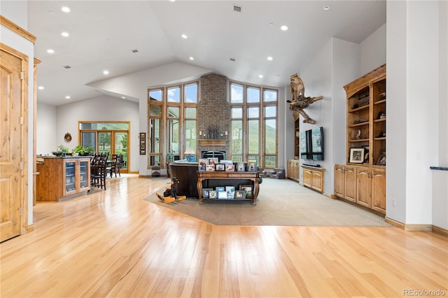 living room featuring light hardwood / wood-style flooring, high vaulted ceiling, and a fireplace