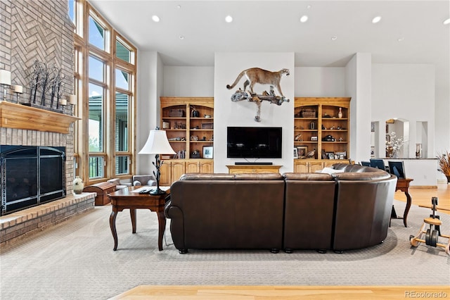 living room featuring a towering ceiling, light hardwood / wood-style flooring, and a brick fireplace